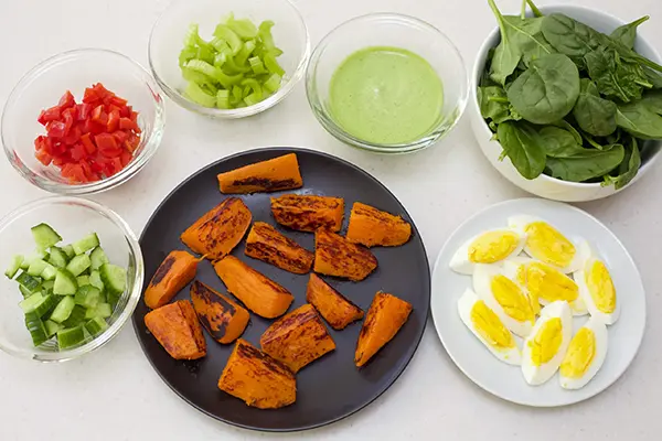 chopped cucumbers, chopped red bell peppers, chopped celery, spinach leaves, hard boiled eggs sliced, grilled sweet potatoes